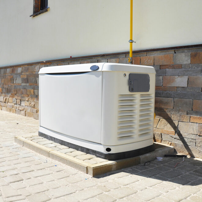 A white generator resting against a house