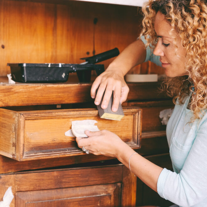 A woman sanding a cabinet draw