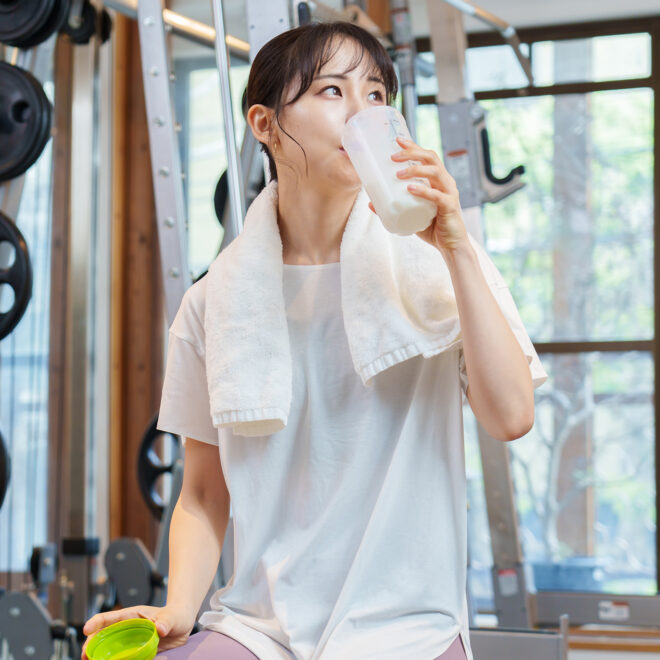 A woman taking a drink of water after working out on her home gym