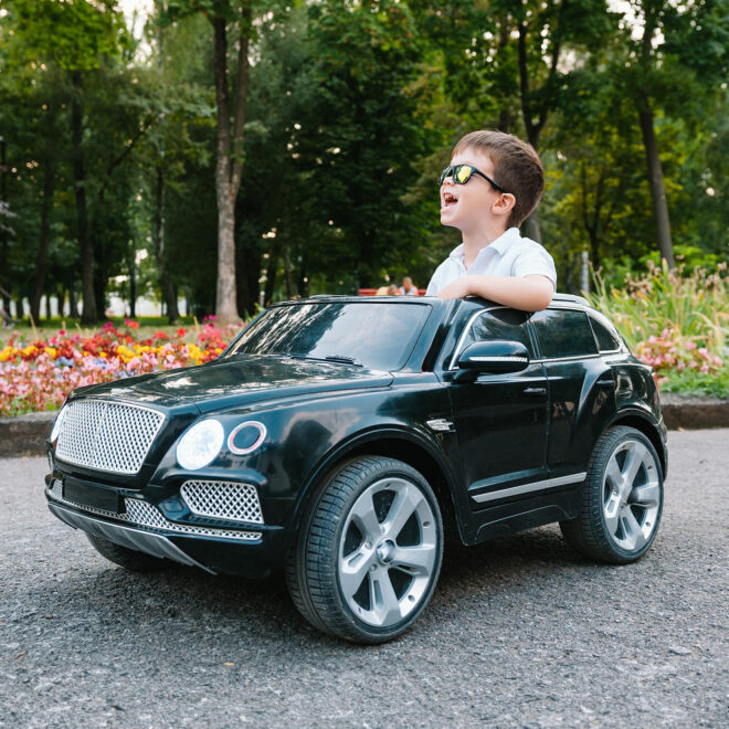 boy in riding a black electric car in the park. Funny boy rides on a toy electric car.