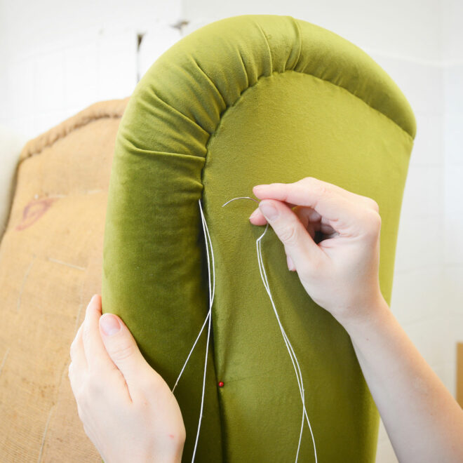 Making new upholstery on old armchair. Green velvet fabric. Restoration of old chair. Woman hands, working in upholstery workshop.