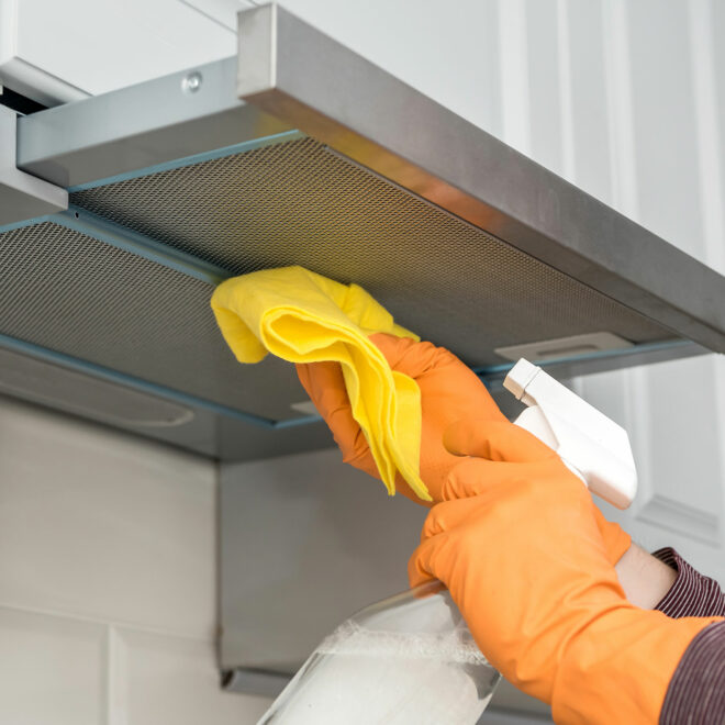 male hands in protective gloves cleaning the kitchen hood with rag and spray bottle